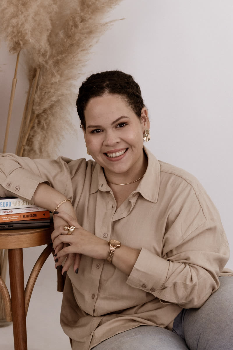 Bianca Siqueira sorrindo, sentada junto a uma mesa